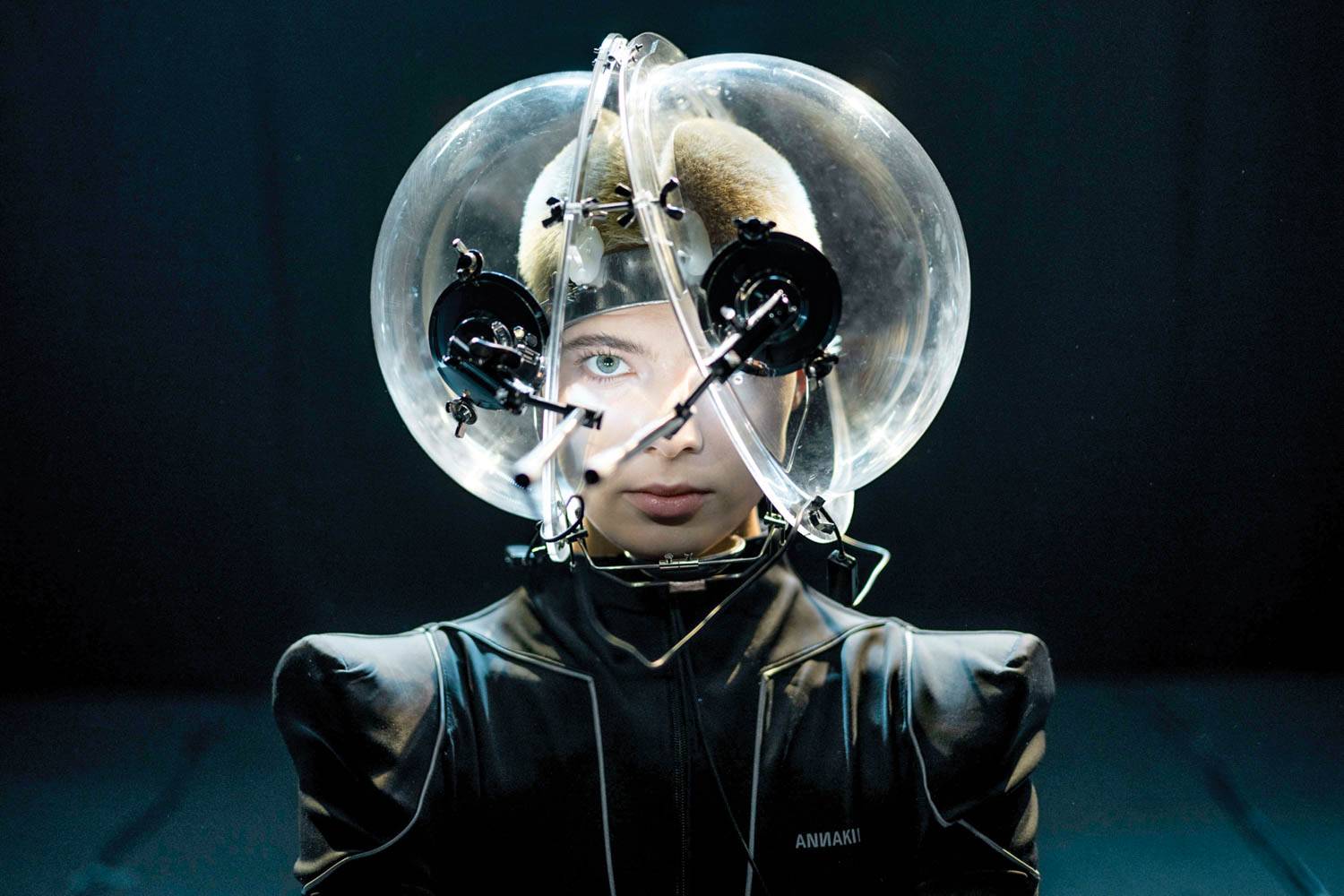 Model wearing an acrylic bubble headpiece fitted with two miniature cameras that captures her eye move­ments