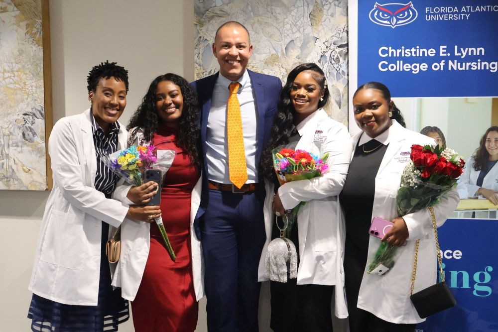 nursing students who received their white coats standing with the dean of the college