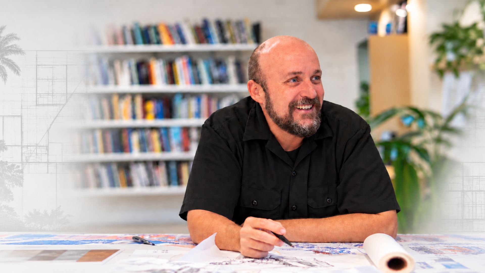 Professor Jeffrey Huber reviews architectural drawings at a design table in a studio setting.