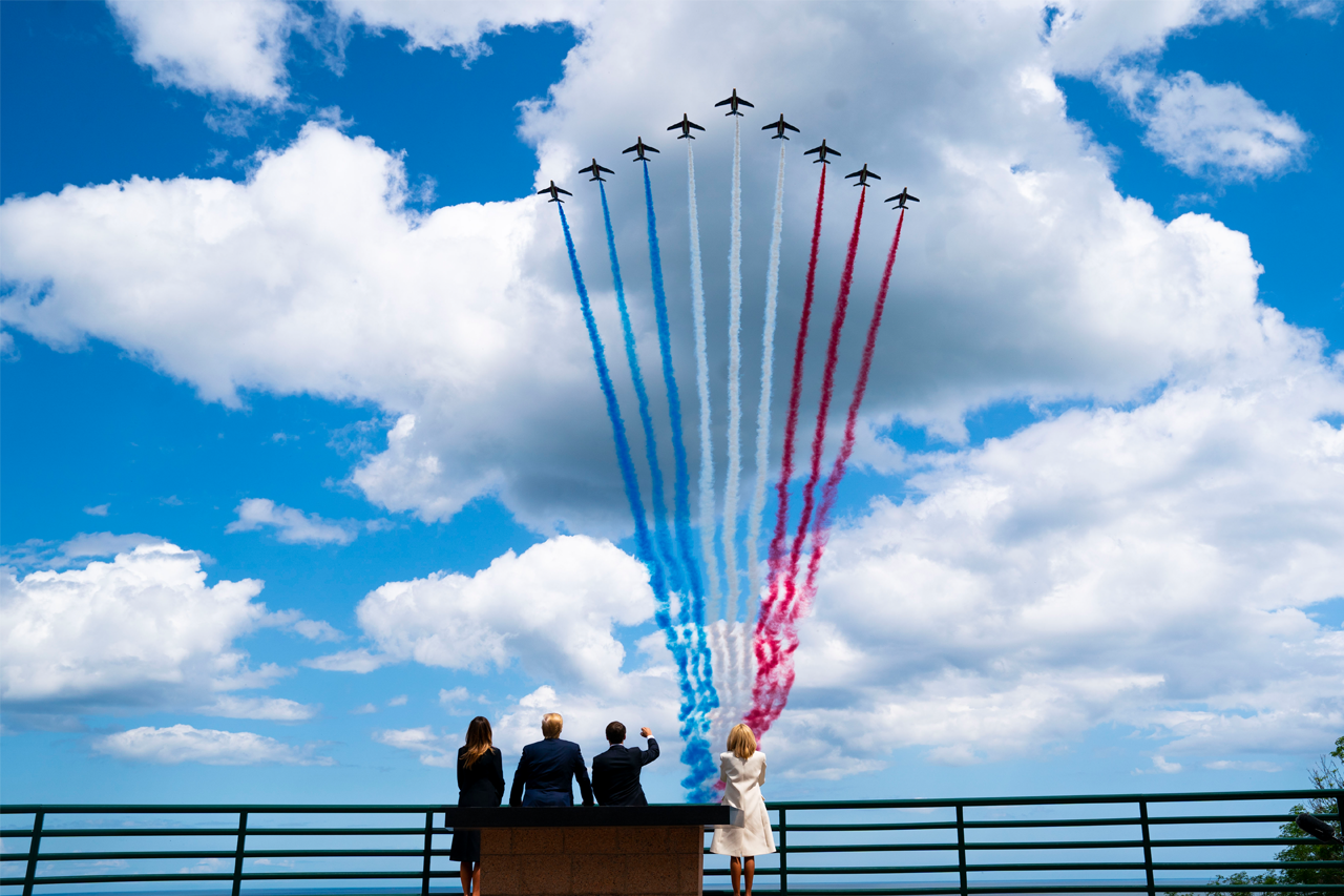 Image of jets with patriotic colored exhaust trails in sky as president Trump and Family look on