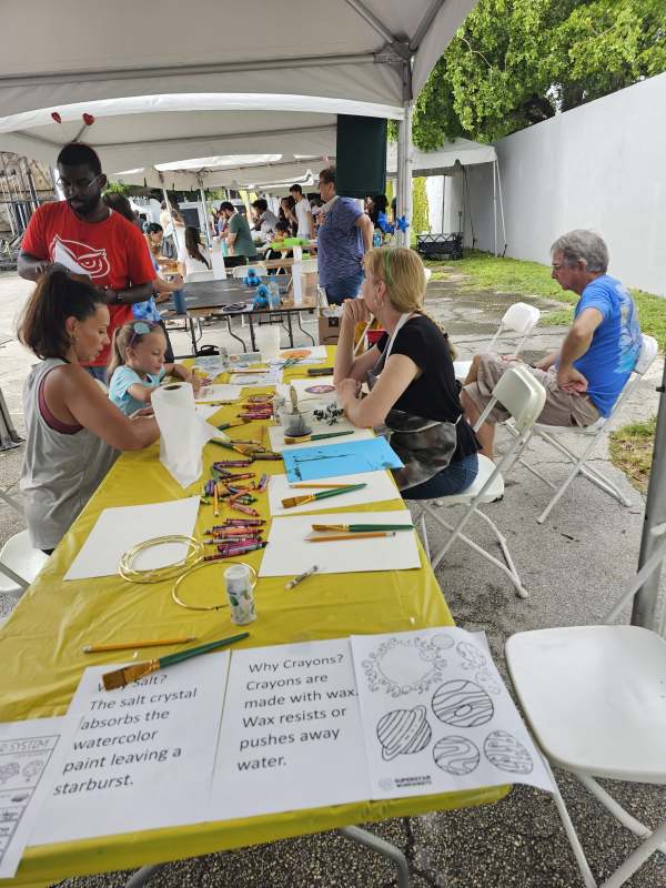 Dr. Susannah Brown (seated right) and Robert Bogle (standing left) guide children through the planet painting activity. 