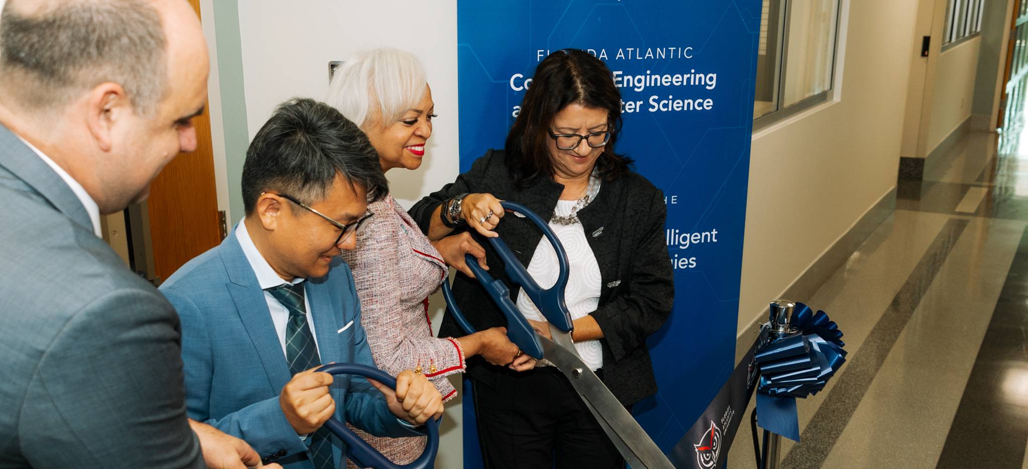 Four people holding a big scissor