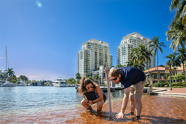 Two FAU students measuring flood water