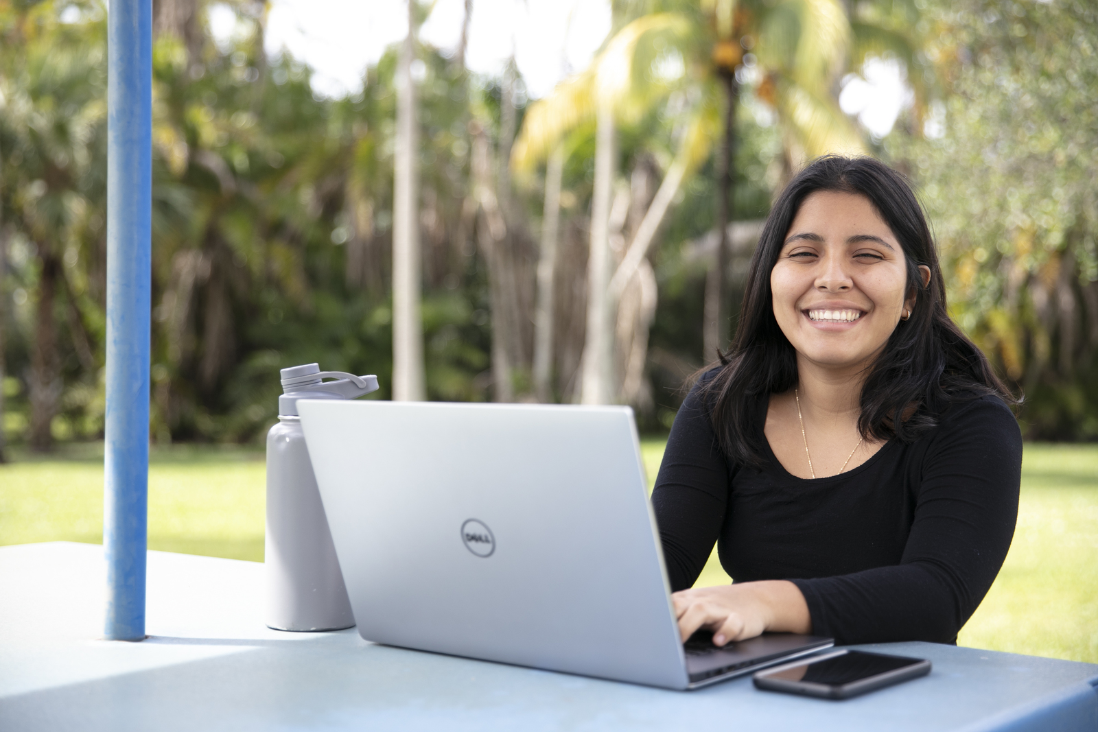 FAU Student smiling with a laptop