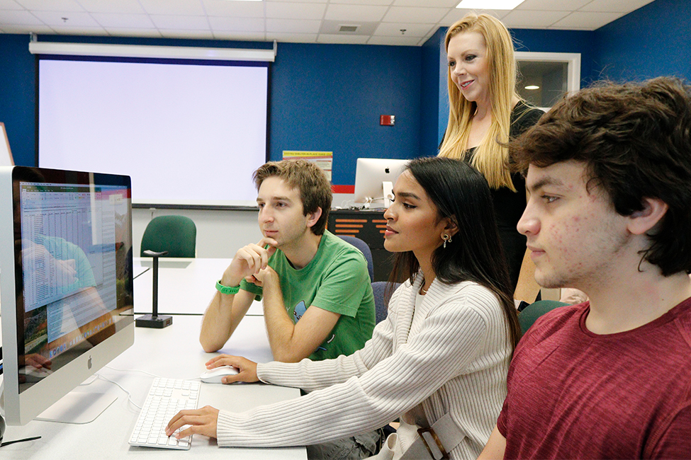 Students on a computer with teacher in classroom