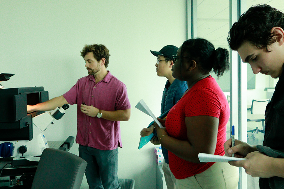 Students watch instructor as he inserts a specimen in a confocal microscope