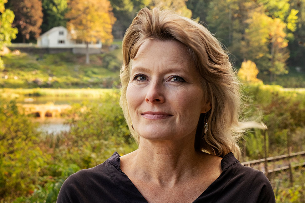 Headshot of author Jennifer Egan posed in front of a rural background.