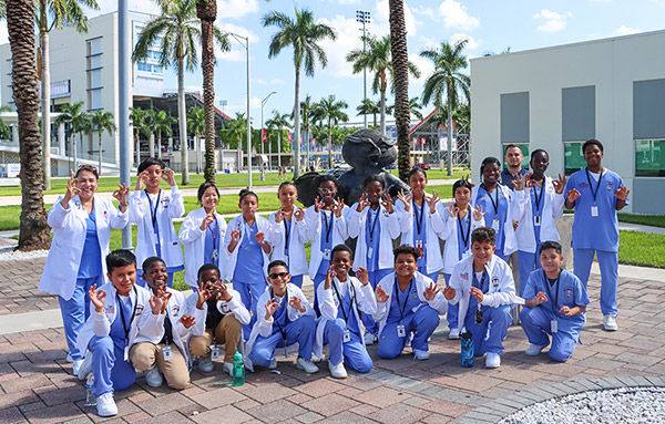 Middle School students taking group photo around the FAU Owl sculpture on Boca Raton Campus