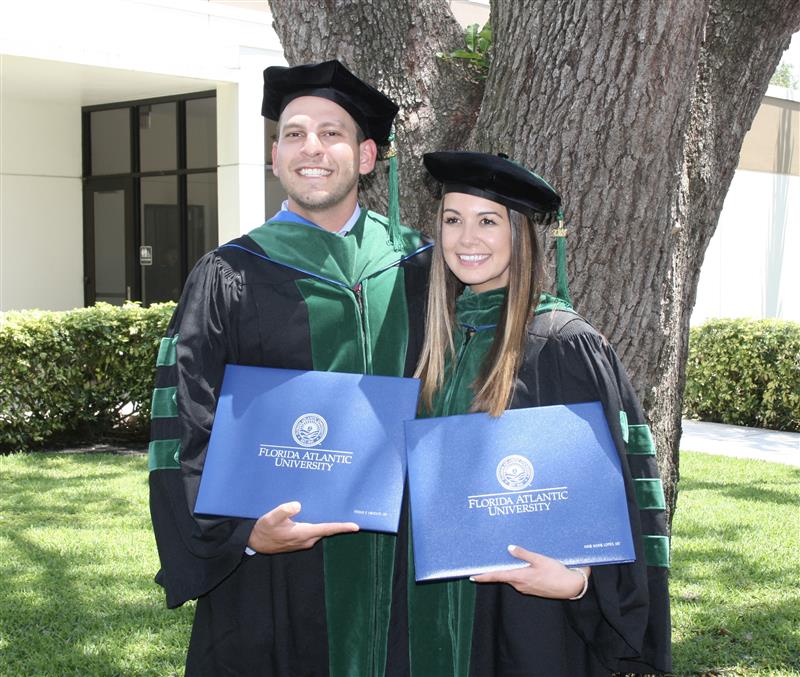 Dr. Kenan Ashouri and Dr. Annie Lopez-Ashouri at graduation posing with diplomas