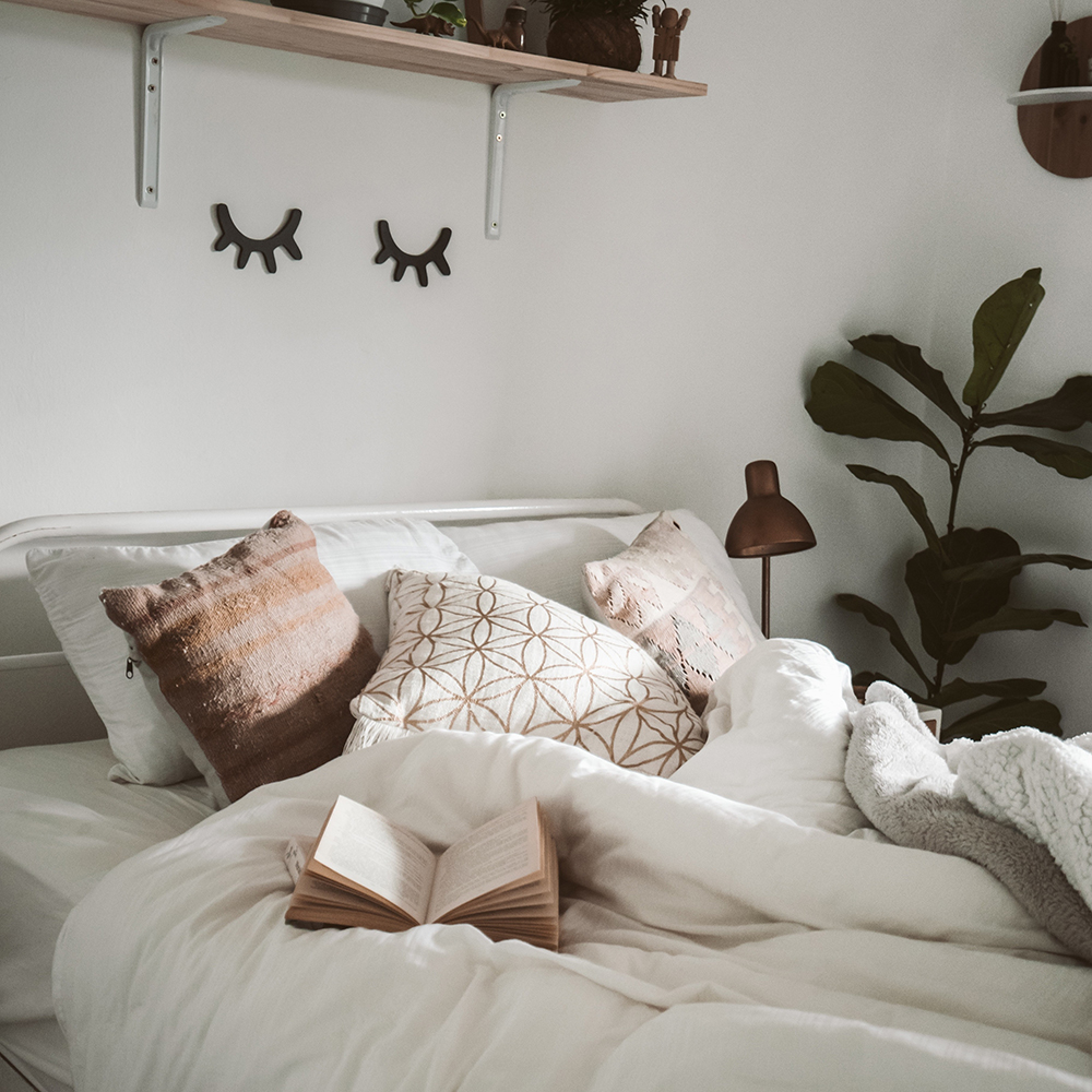 bed with book and sleepy eye art on wall