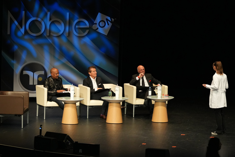 A panel of three judges listen to a pitch from a scientist. 