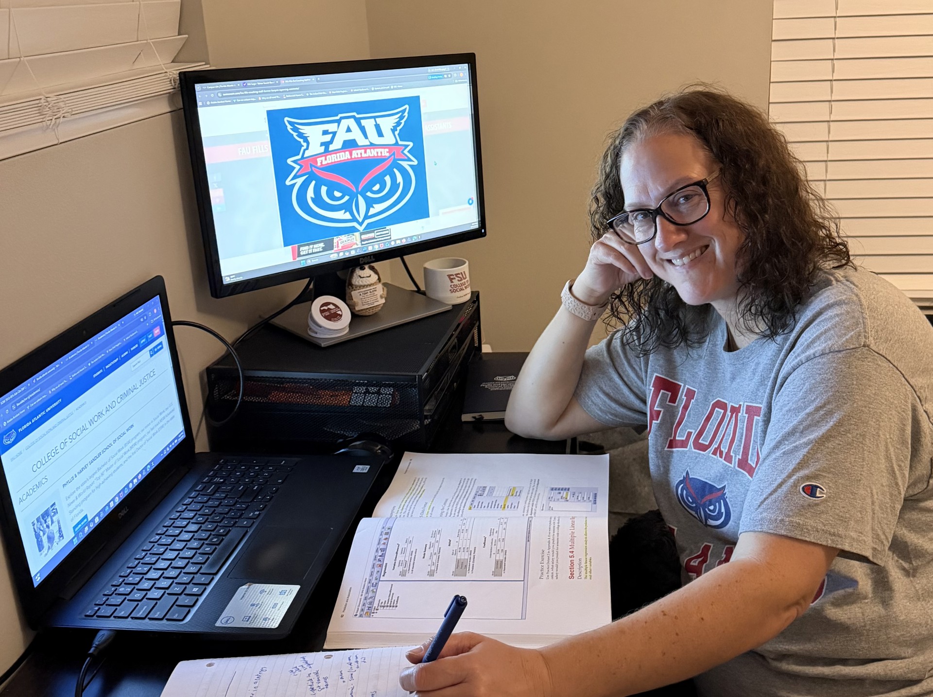 Kimberly Harvey smiling at her home desk with a laptop, an FAU logo on her monitor, and open course notes